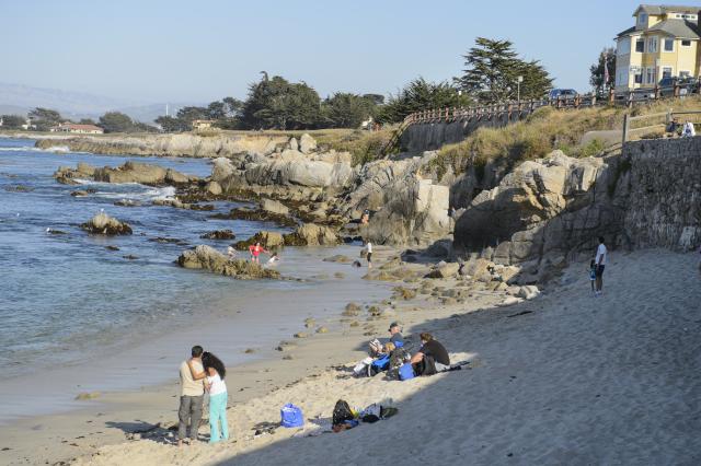 Visitors enjoy the sandy beach and sights of Lovers Point in Pacific Grove.