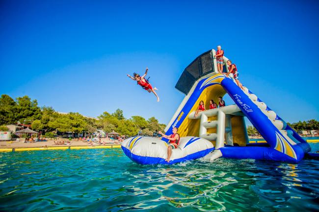 Kids play on a tall, inflatable playset that floats on the water at Splash Aqua Park