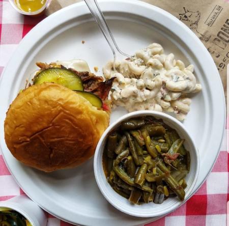 plate of food at pickles and bones in milford ohio featuring green beans and BBQ sandwich