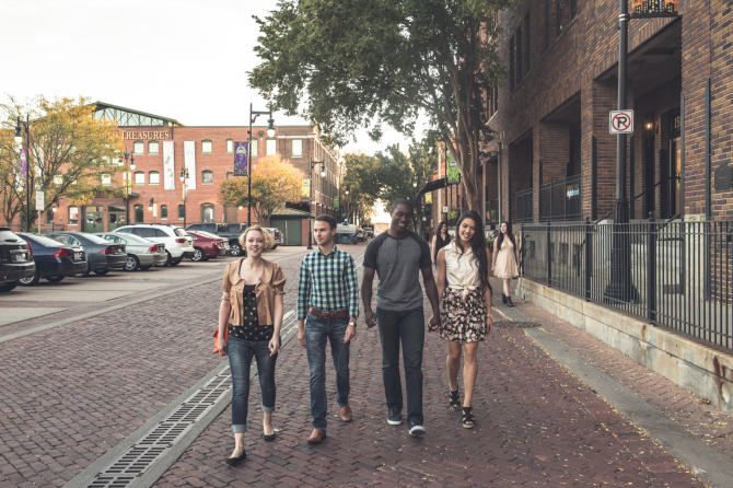 A group of four friends walk the brick roads of Old Town in Wichita