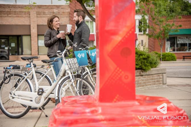 A man and woman enjoy a hot beverage in Old Town Wichita while taking a break on their bike ride with bikes from Bike Share ICT
