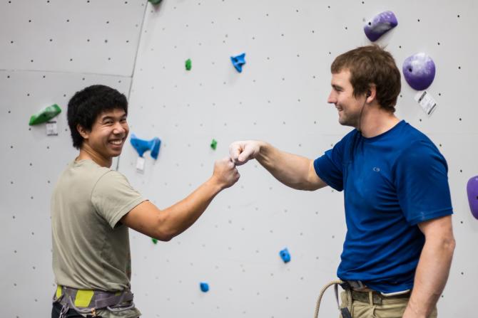 Two guys bump knuckles before climbing the wall at Bliss Boulder and Fitness