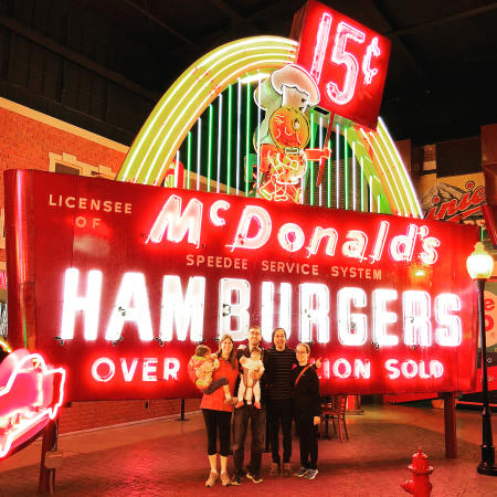 photo of family with kids touring the american sign museum in cincinnati ohio standing in front of a vintage mcdonalds hamburgers sign
