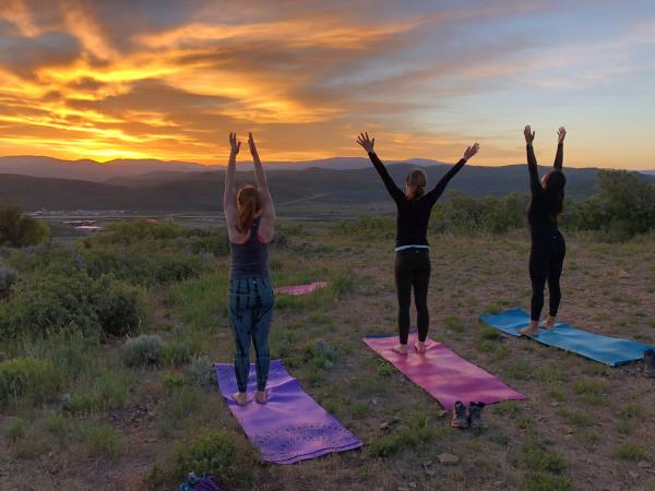 Three people doing yoga at sunrise
