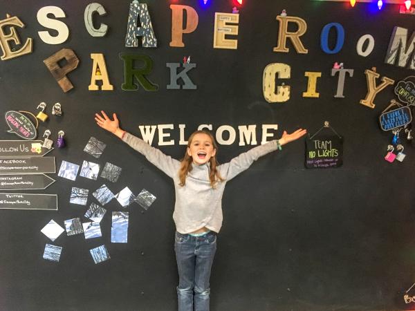 Girl stands in front of a sign that reads escape room