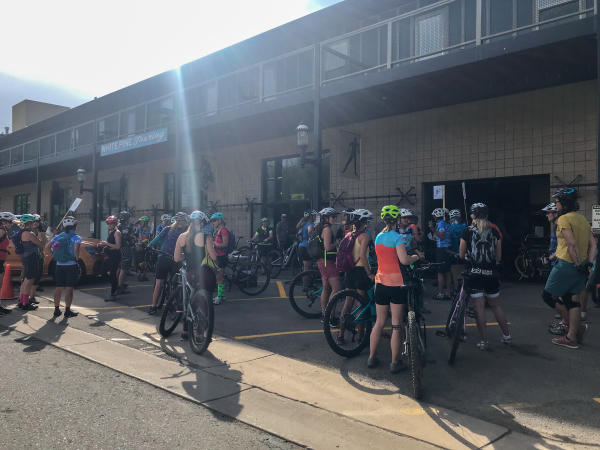Group of Women Mountain Bike Riders gather outside shop