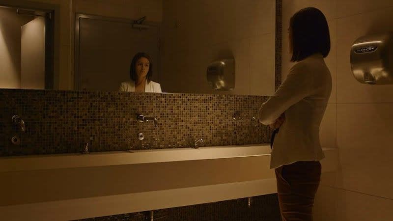 Woman looking in bathroom mirror in film still for Cine Las Americas Virtual Showcase