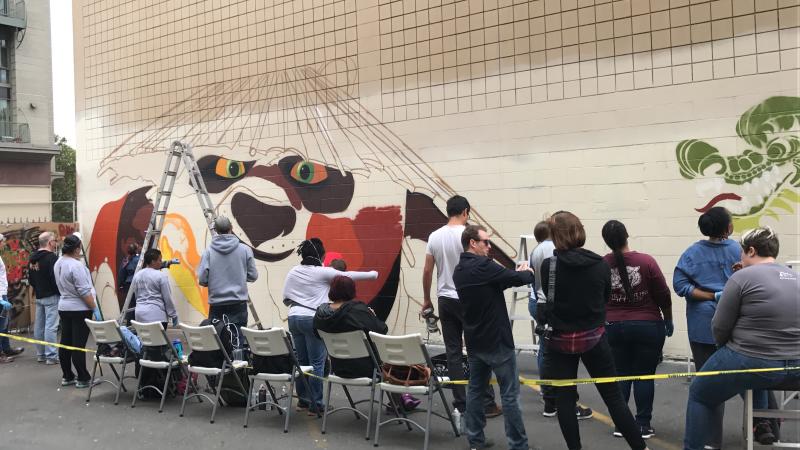 Volunteers Help Paint a Mural With Dragon School