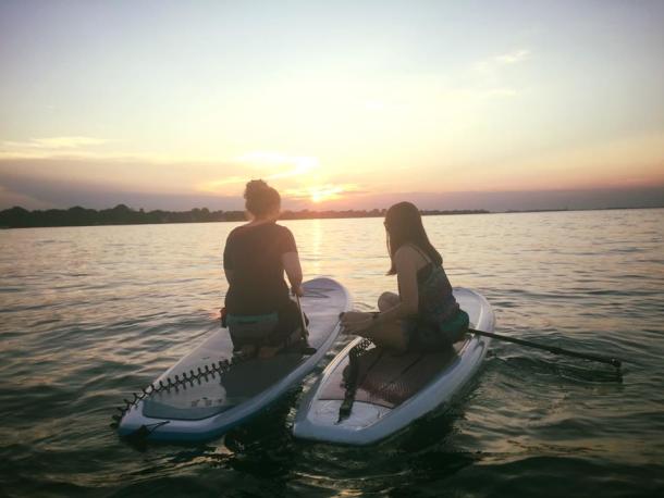 people on paddleboards watching sunset in the distance