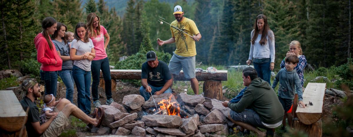 People gathered around a fire roasting marshmallows in the Tushar Mountains