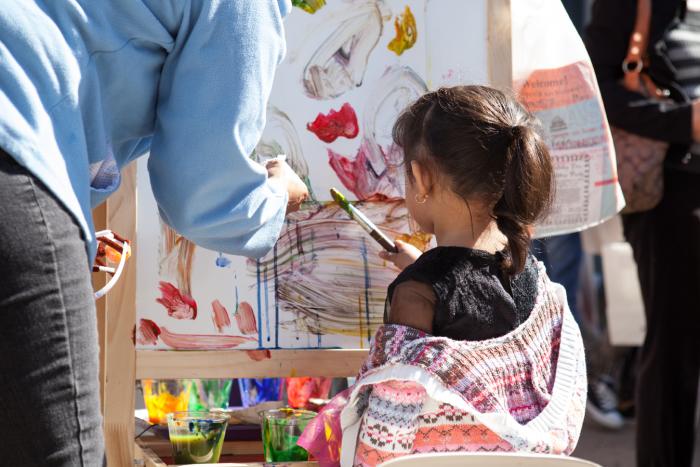 Parent and child enjoy painting outdoors a Texas art event.
