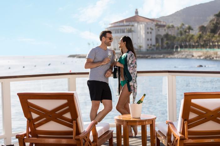 Couple on a cabana deck with chaise lounges overlooking the ocean at Descanso Beach Club on Catalina Island