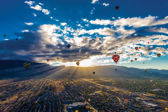 balloons and sun rising over sandia mountains