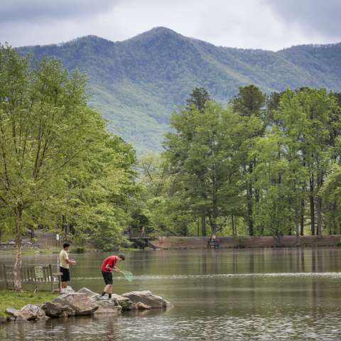 two people fishing on a rock