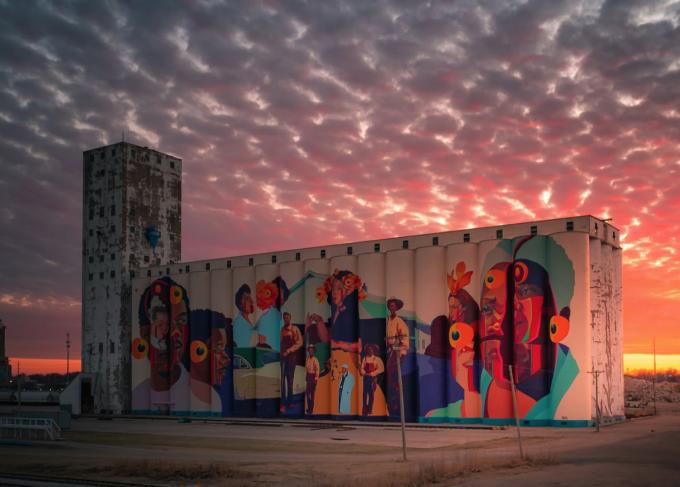 The Horizontes mural from a distance with a pink, orange, and purple sunset