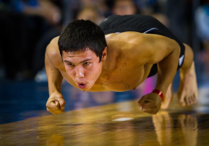 athletic young man hopping across a wooden floor on knuckles and toes