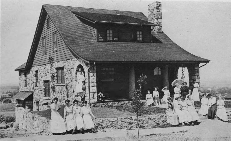 Black and white photo of Bluebird Cottage with several women sitting out front