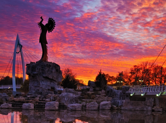 The Keeper of the Plains stands under a beautiful purple and orange sunset in Wichita