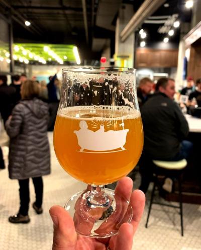 Hand holding glass of beer in front of camera with patrons in background at Taft's Brewporium in Franklinton