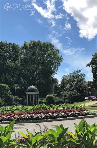 Entrance to Congress Park lined with beds of green plants and red and white flowers.