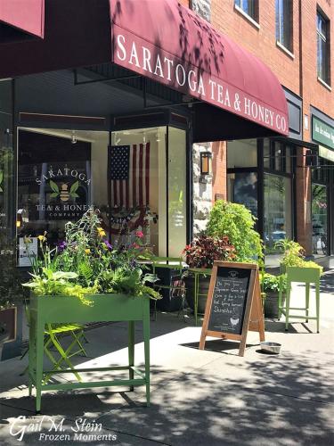 Exterior shot of Saratoga Tea and Honey with plants and flowers surrounding the entrance