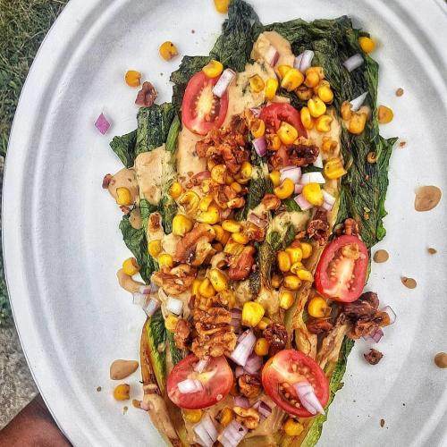 A dish of roasted greens & corn topped with cherry tomatoes from the vegan food truck Sprouting Dreams.