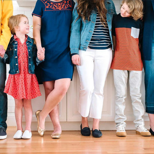 a family standing in a line with two children looking at each other