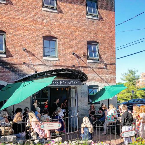 Group of people surrounded by Farmers Hardware entrance and patio with green umbrellas