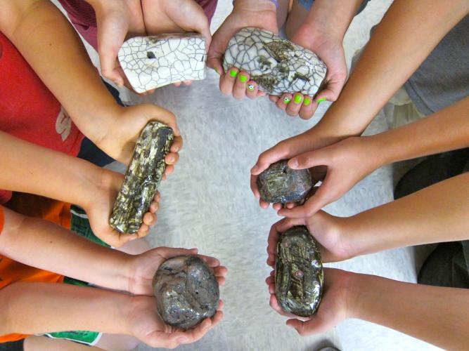 Circle of hands holding clay