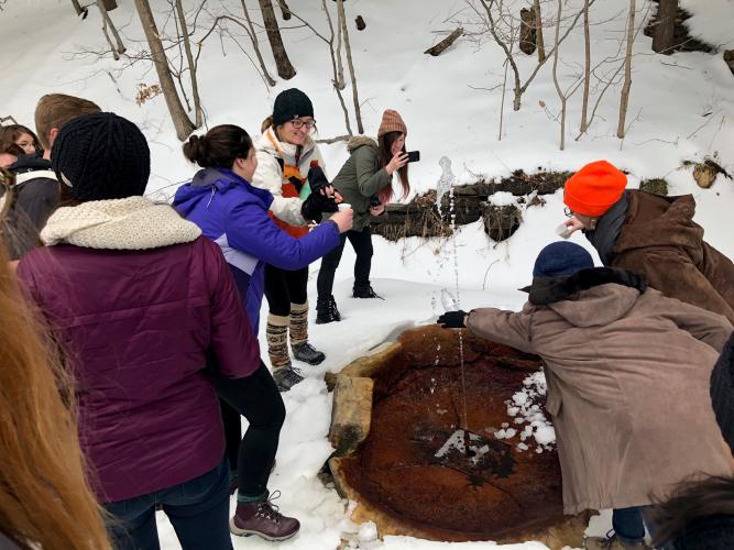 People surrounding a spring at the State Park as part of a winter tour