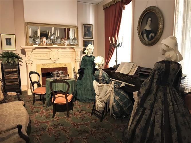 Walworth Mansion in piano room with 3 women standing around piano
