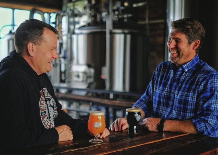 Two men sitting at bar at Hank Hudson Brewing with two beers on the bar in front of them