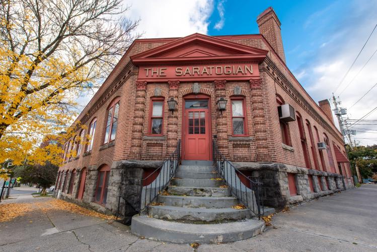 Exterior shot of the Old Saratogian bldg, with a bright yellow tree on one side and a blue sky