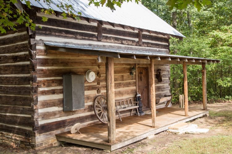 The front entrance of a log cabin in the woods.