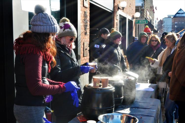 Girls serving steaming chowder in the sunlight