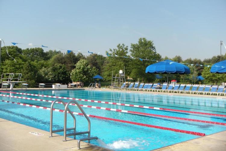 A bright blue pool surrounded by chairs and umbrellas