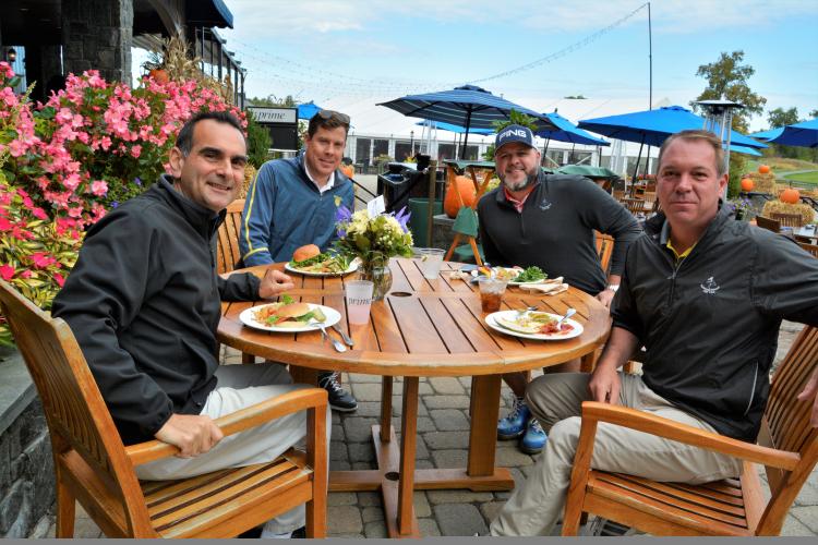 Four guys sitting at a table eating lunch on the patio at National
