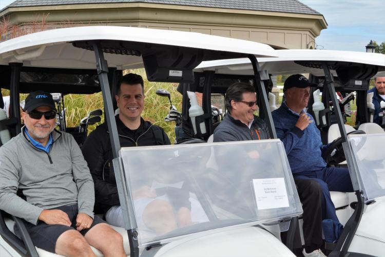 Foursome of guys sitting in two golf carts