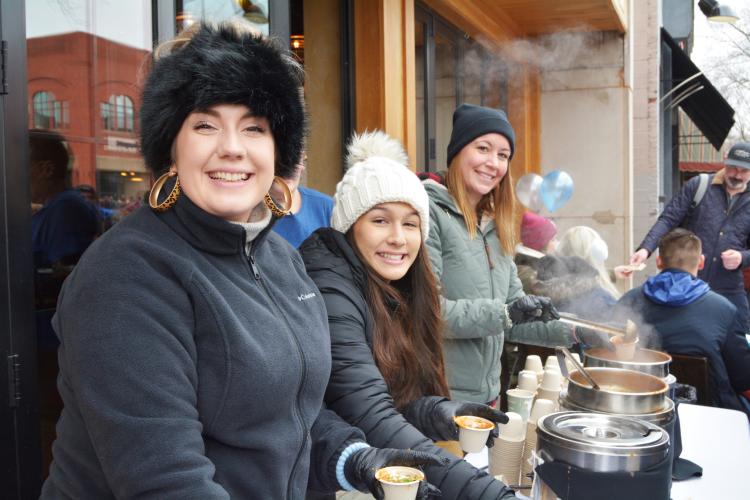 Three women serving hot chowder
