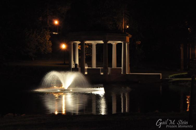 War Memorial and fountain in pond lit up at night