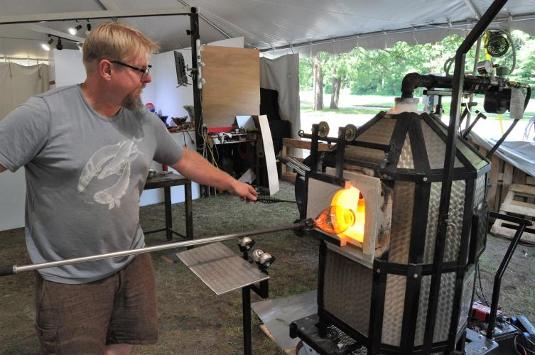 Greg Tom inserting a glass piece into the furnace