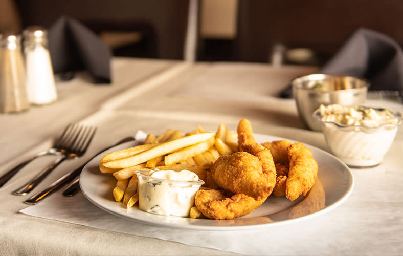 A plate of fried fish with tartar sauce and french fries