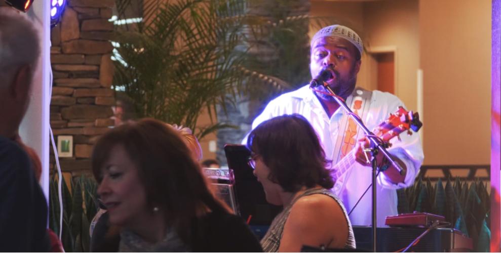 Garland Nelson at Diamond Club wearing a white shirt, holding his guitar and singing into the mic