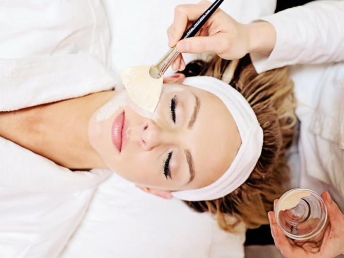 A woman relaxes at a spa while getting a facial