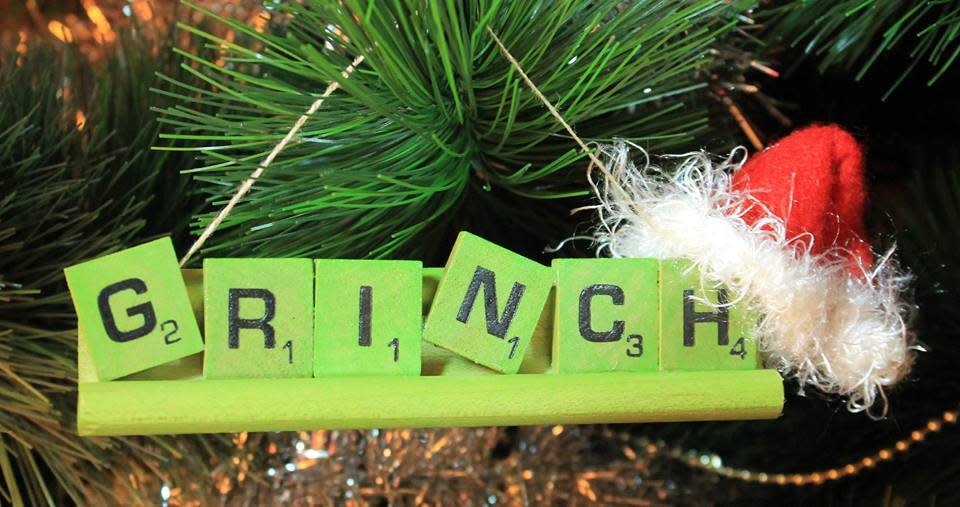 Christmas tree ornament made out of Scrabble pieces that spells out "GRINCH" with a Santa hat on the right corner.