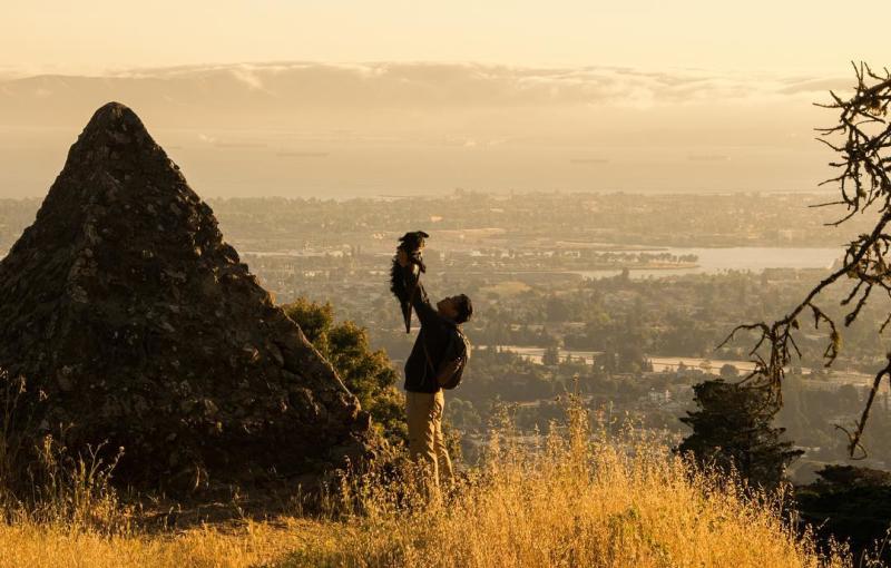 A man holding his dog next to the Pyramid of Moses at Joaquin Miller Park