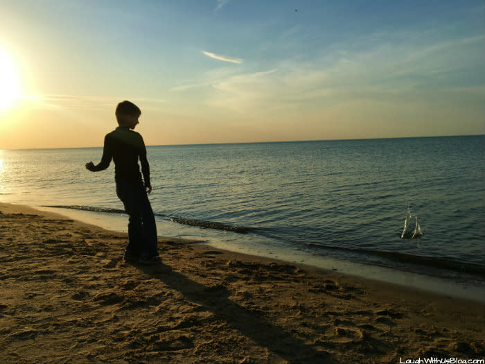 Boy tries to skip rocks at the Indiana Dunes West Beach in Northwest Indiana at sunset
