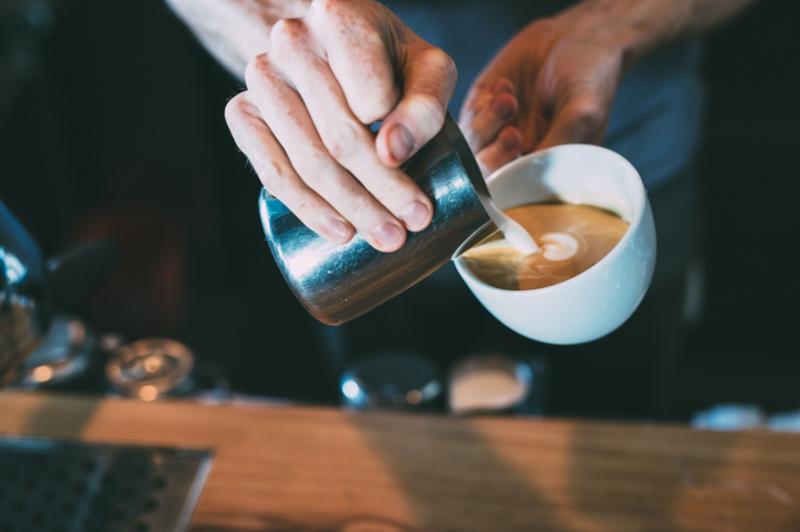 Barista pours milk for cappuccino at The Brew and Brew
