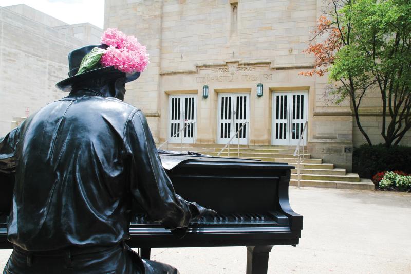 Statue of Hoagy Carmichael playing the piano with pink flowers in his hat