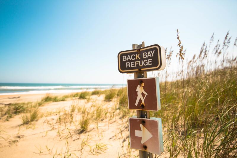 A weathered sign guides hikers towards the Back Bay Refuge trail.